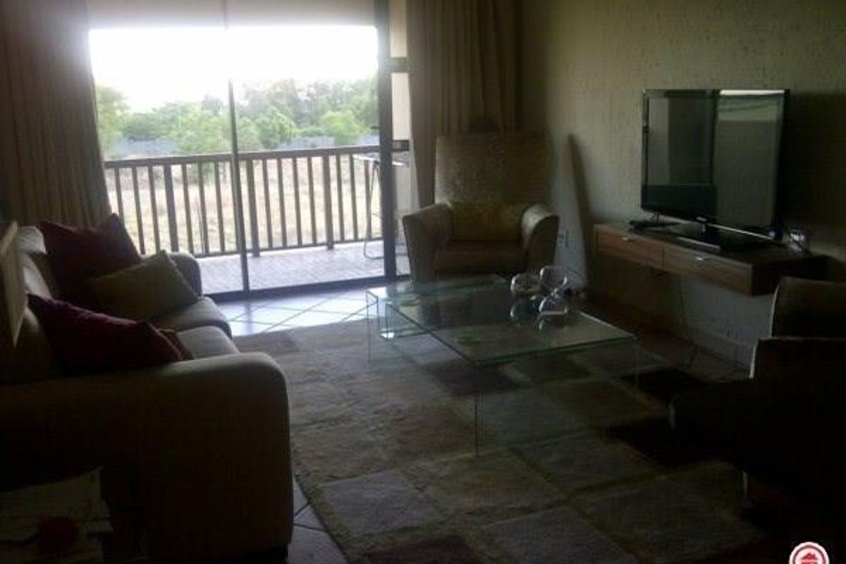 A living room featuring tiled flooring, a floating media console, and a large sliding glass door providing access to an outdoor balcony.
