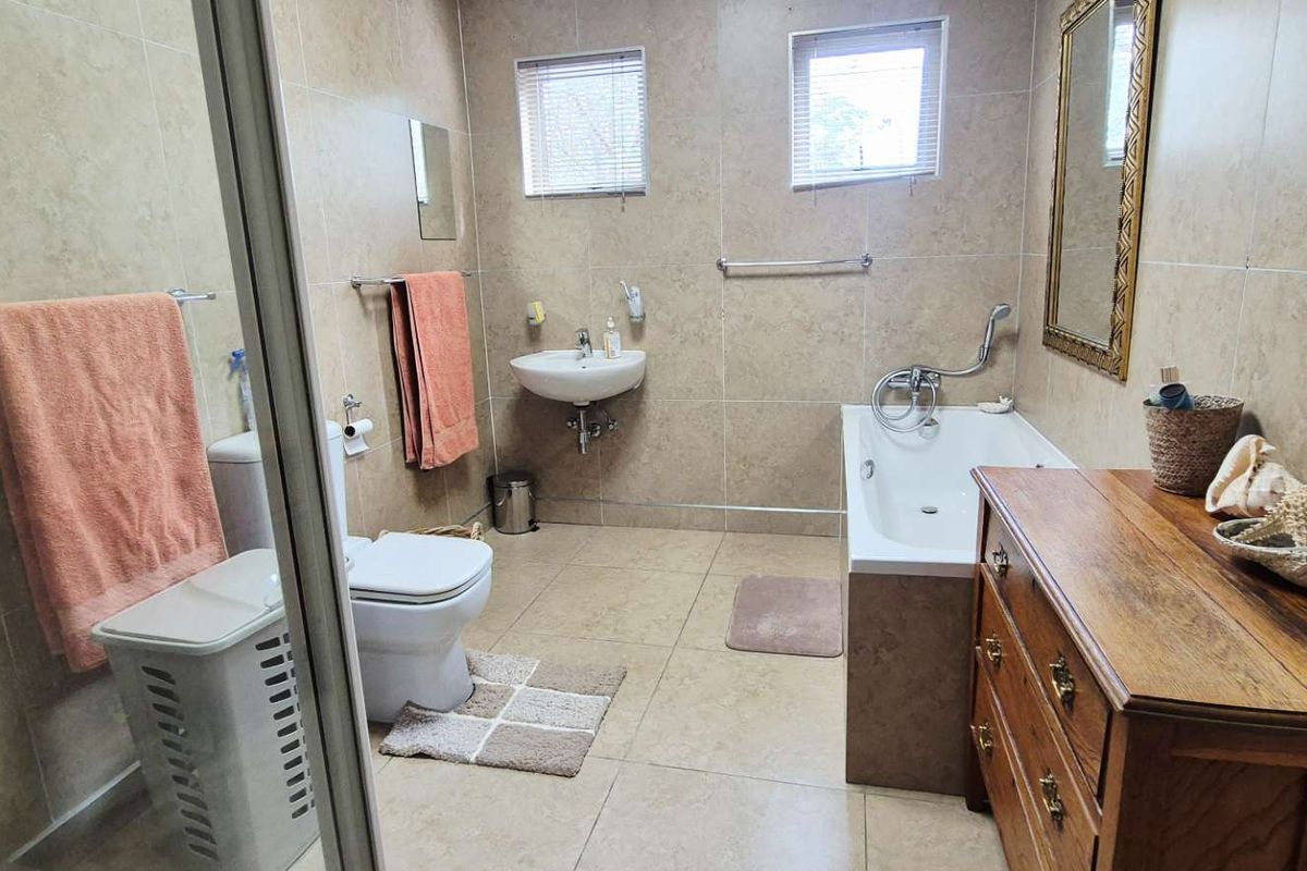 A functional bathroom featuring floor-to-ceiling tiling, a built-in bathtub, a wall-mounted basin, and a separate shower enclosure.