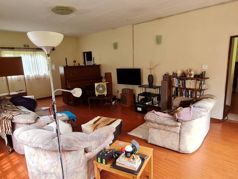 A spacious living room featuring laminate flooring and neutral wall finishes, offering a functional layout with potential for modern updates.