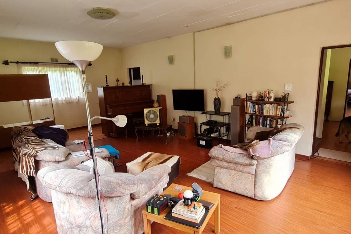 A spacious living room featuring laminate flooring and neutral wall finishes, offering a functional layout with potential for modern updates.