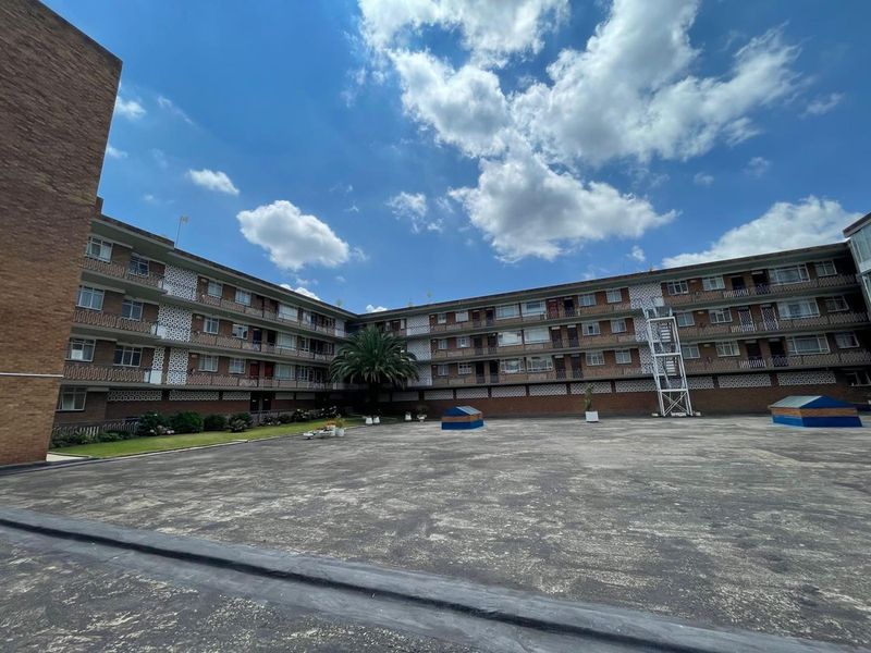 A view of the rear courtyard and brick apartment building facade featuring multiple balconies and decorative architectural elements.