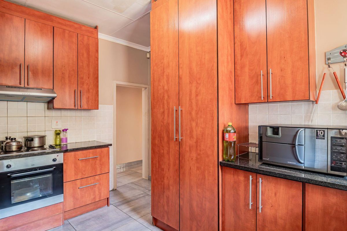A functional kitchen featuring cherry-wood cabinetry, granite countertops, a built-in oven, and a stainless steel extractor fan.