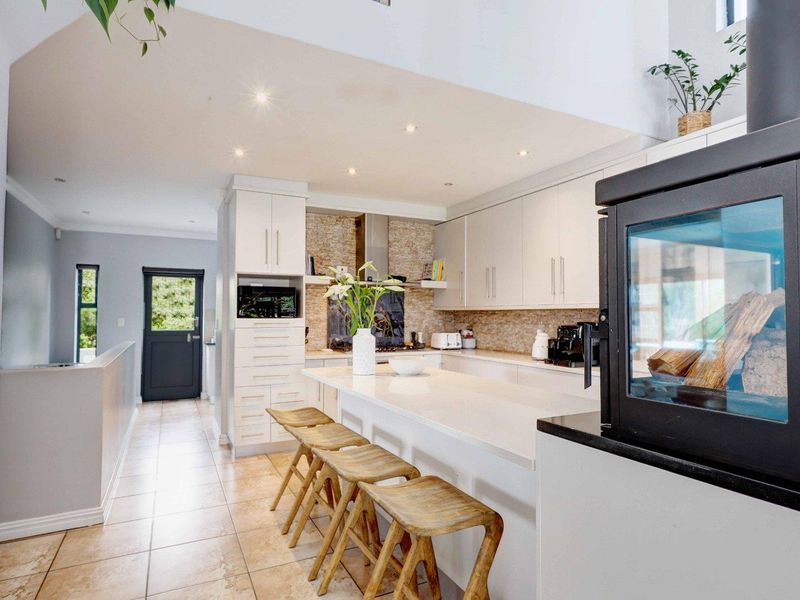 Modern kitchen featuring a central island with stone countertops, ample built-in cabinetry, tiled flooring, and a cozy fireplace, creating a functional and inviting space.