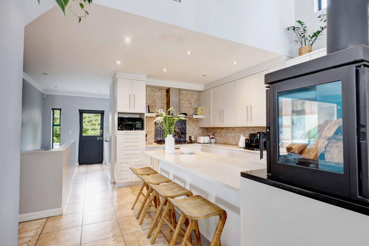 Modern kitchen featuring a central island with stone countertops, ample built-in cabinetry, tiled flooring, and a cozy fireplace, creating a functional and inviting space.