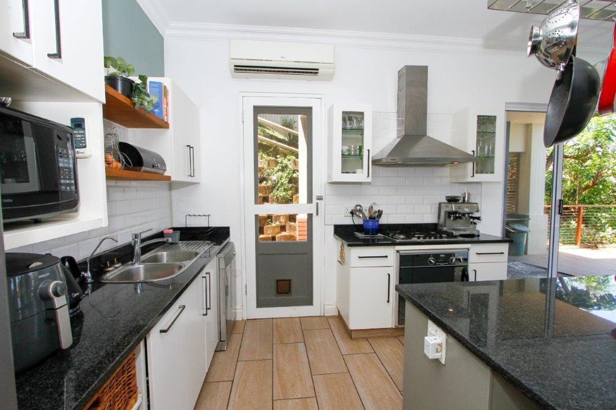 A functional kitchen featuring granite countertops, subway tile backsplash, stainless steel appliances, and direct access to an outdoor patio area.