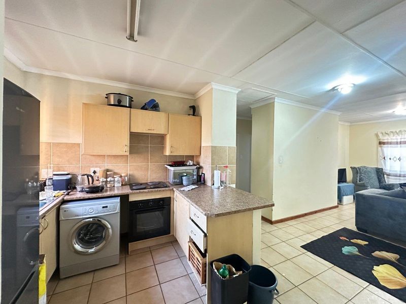 Open plan kitchen and living area featuring tiled flooring, built-in cabinetry, and integrated oven and hob, offering a functional layout for daily living.