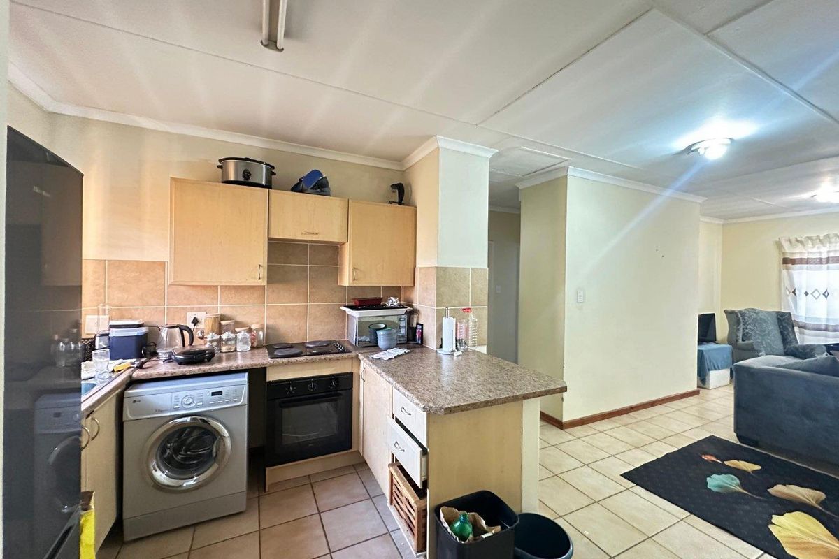 Open plan kitchen and living area featuring tiled flooring, built-in cabinetry, and integrated oven and hob, offering a functional layout for daily living.