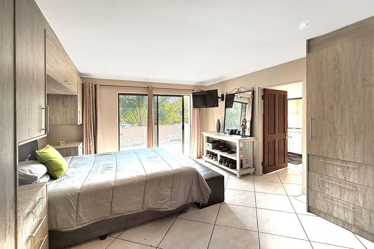 Spacious bedroom featuring built-in wooden cabinetry, tiled flooring, and sliding glass doors providing access to an outdoor balcony area.