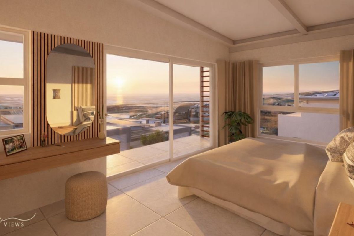 A modern bedroom featuring large sliding glass doors that open to a balcony with expansive coastal views and tiled flooring.