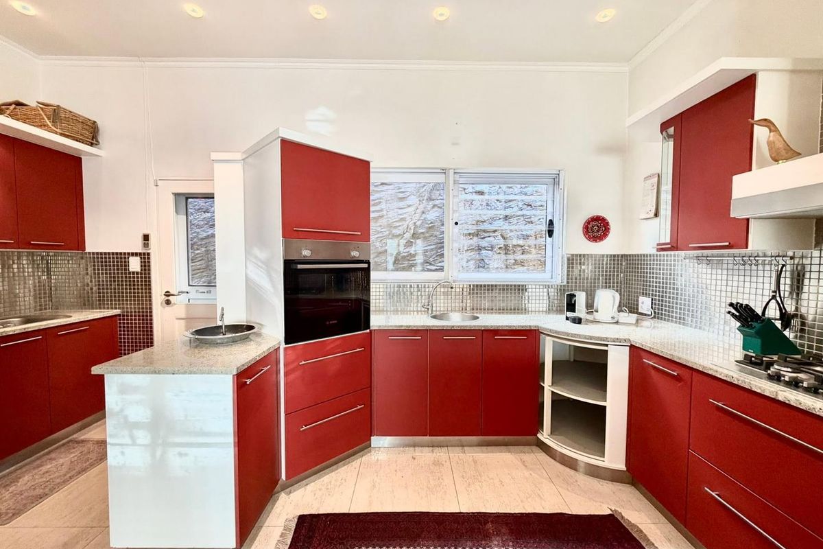 A kitchen featuring red cabinetry, granite countertops, mosaic tile backsplash, built-in oven, and recessed ceiling lighting.