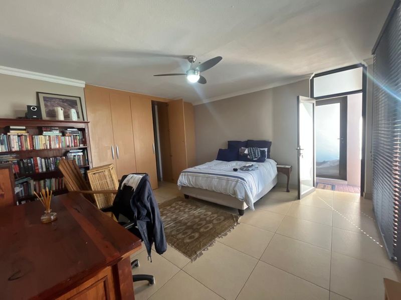 Spacious bedroom featuring built-in cupboards, tiled flooring, a ceiling fan, and direct access to an outdoor patio area.