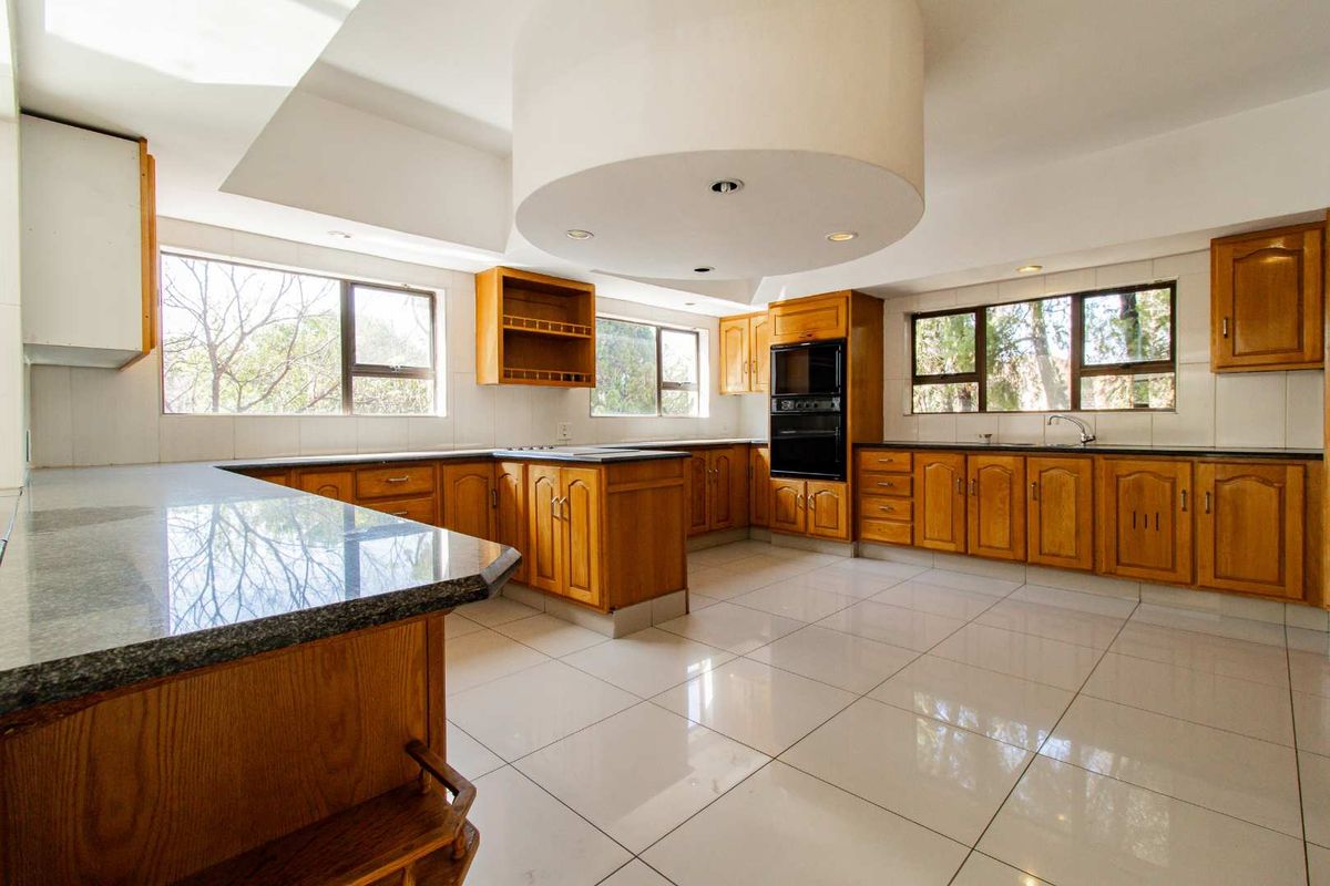 Spacious kitchen featuring wooden cabinetry, granite countertops, built-in oven, and large tiled flooring with a unique circular ceiling feature.