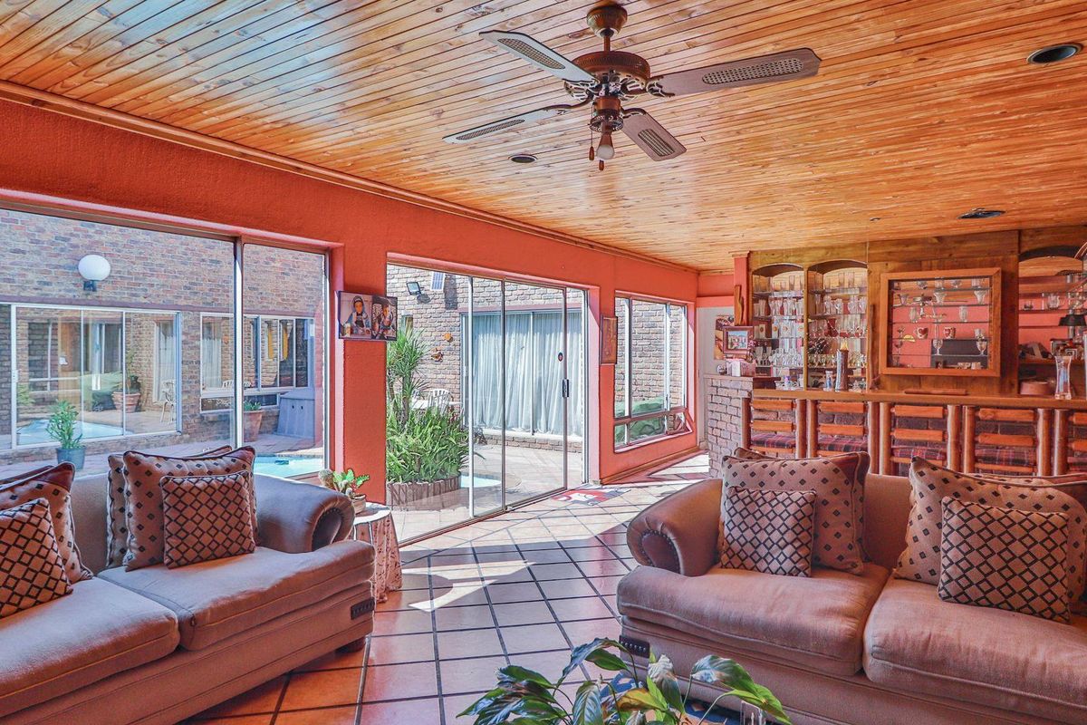Spacious living area featuring a built-in wooden bar, timber-clad ceiling, and large sliding glass doors providing direct access to the pool and patio area.