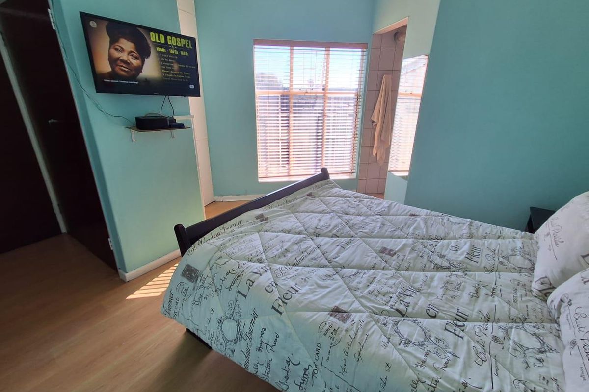 A bedroom featuring laminate flooring, a window with fitted blinds, and an en-suite bathroom access point.