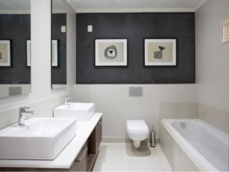Modern bathroom featuring a double vanity with vessel sinks, a wall-mounted toilet, and a built-in bathtub with clean, contemporary finishes.