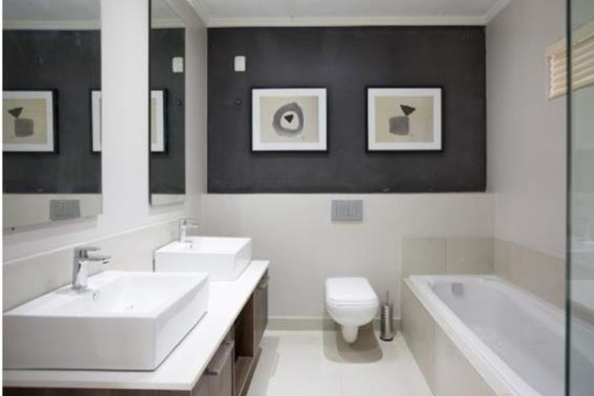 Modern bathroom featuring a double vanity with vessel sinks, a wall-mounted toilet, and a built-in bathtub with clean, contemporary finishes.