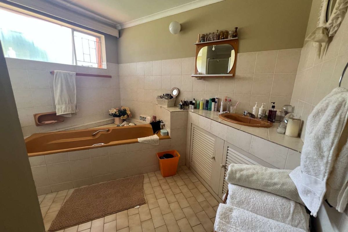 A dated bathroom featuring a built-in bathtub, vanity with integrated sink, and tiled surfaces throughout.