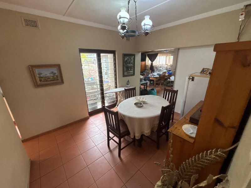 Dining area featuring ceramic tile flooring and a glass sliding door providing access to the exterior, with an adjacent view into another living space.