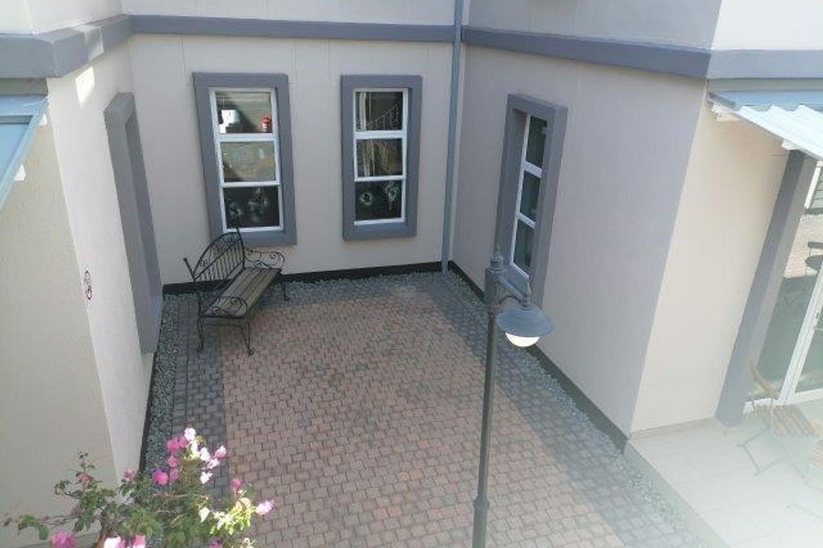 A paved rear courtyard area featuring exterior lighting and access to the office building through multiple windows.