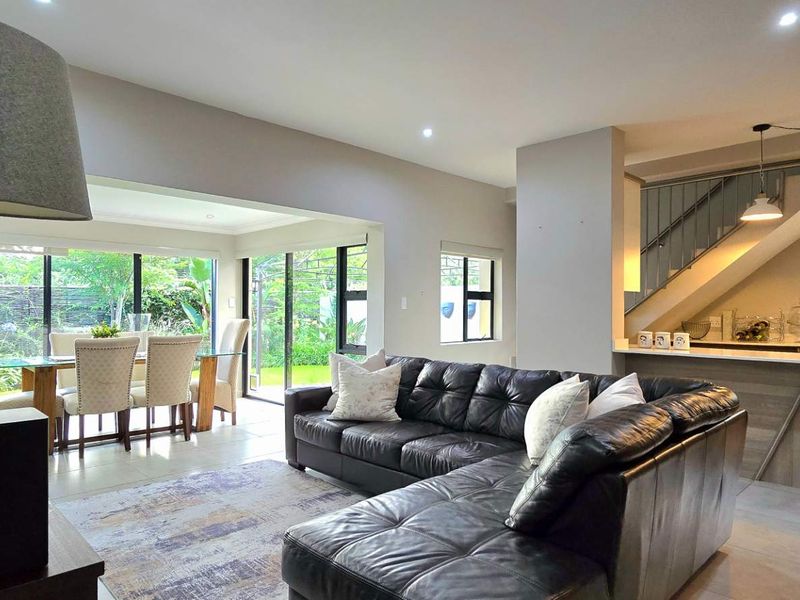 Spacious open-plan living and dining area featuring tiled floors, recessed lighting, and a modern kitchen with an island, flowing seamlessly to the rear garden.