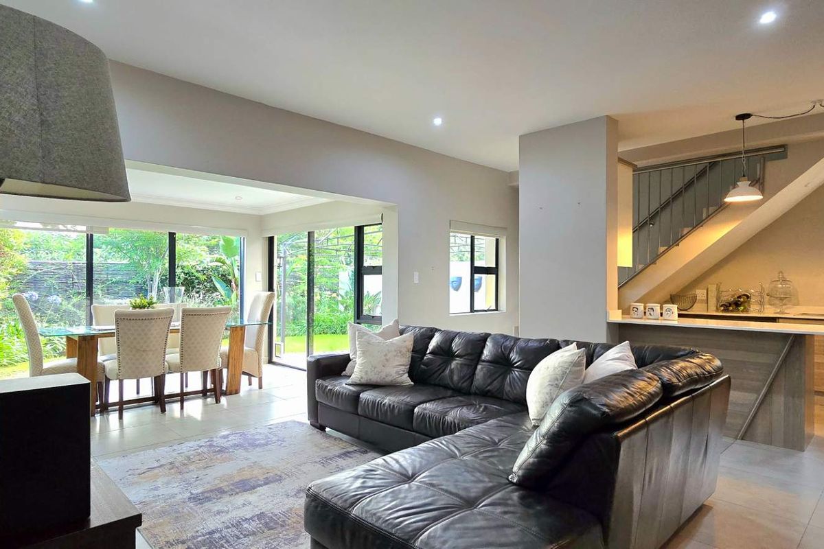 Spacious open-plan living and dining area featuring tiled floors, recessed lighting, and a modern kitchen with an island, flowing seamlessly to the rear garden.