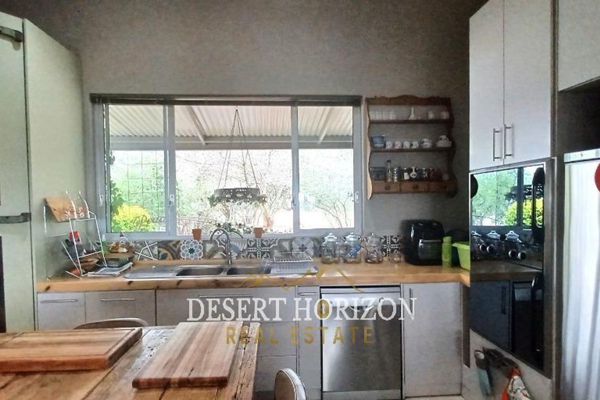 A functional kitchen featuring wooden countertops, a double sink, built-in cabinetry, and a window overlooking the outdoor area.