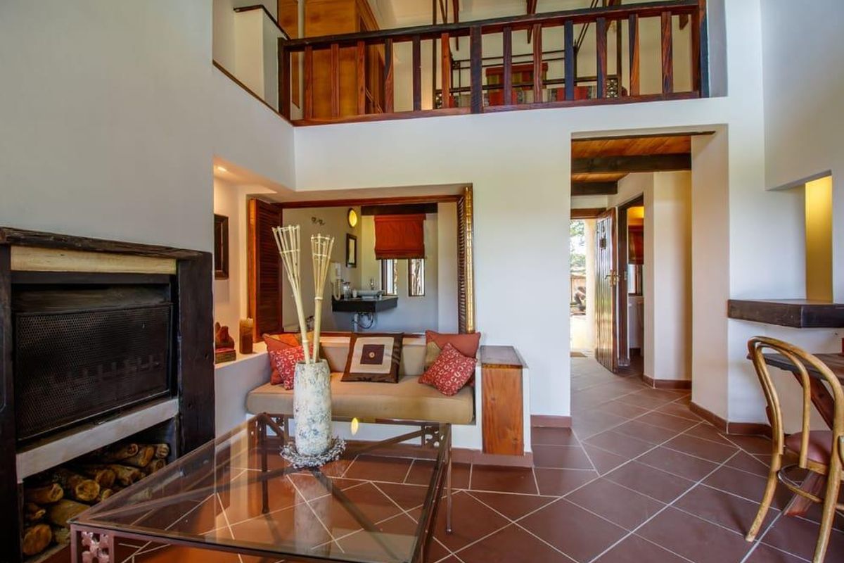 A cozy living area featuring a built-in fireplace, tiled flooring, and a mezzanine level with wooden railings, creating a warm and rustic atmosphere.