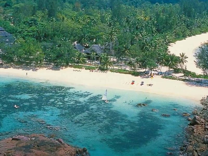 Aerial view of a pristine coastal property featuring white sandy beaches, lush tropical vegetation, and clear turquoise waters.