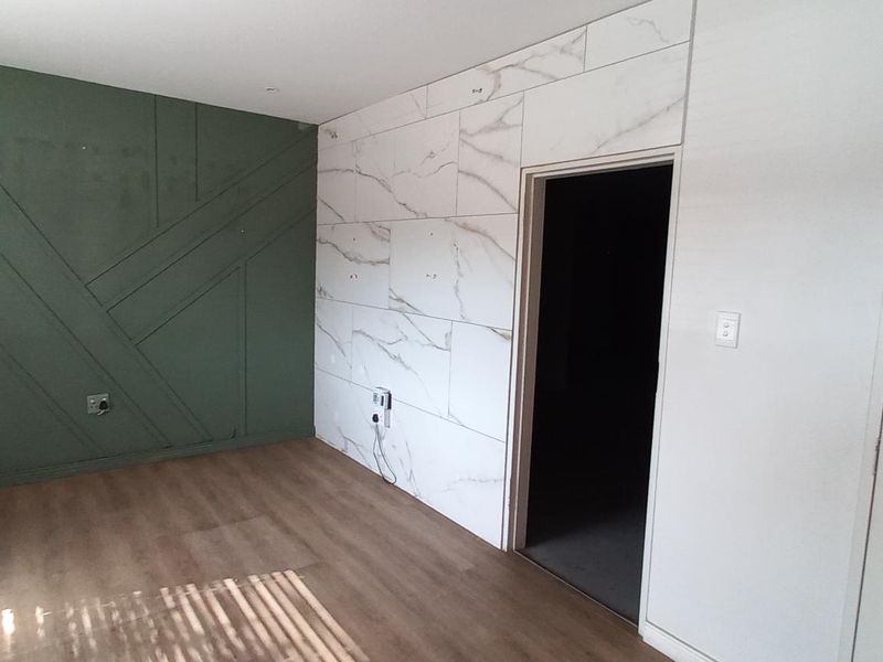 Interior space featuring a decorative green accent wall with geometric paneling and a contrasting marble-effect tiled feature wall with a doorway.