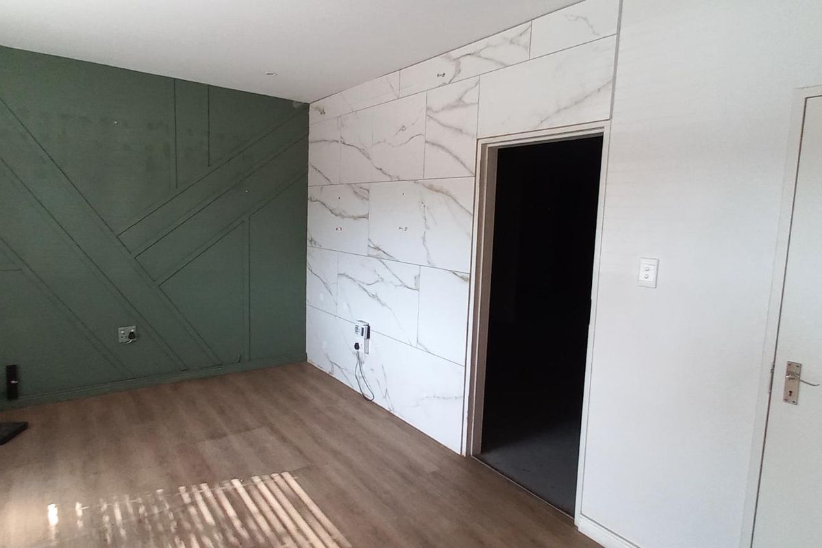 Interior space featuring a decorative green accent wall with geometric paneling and a contrasting marble-effect tiled feature wall with a doorway.