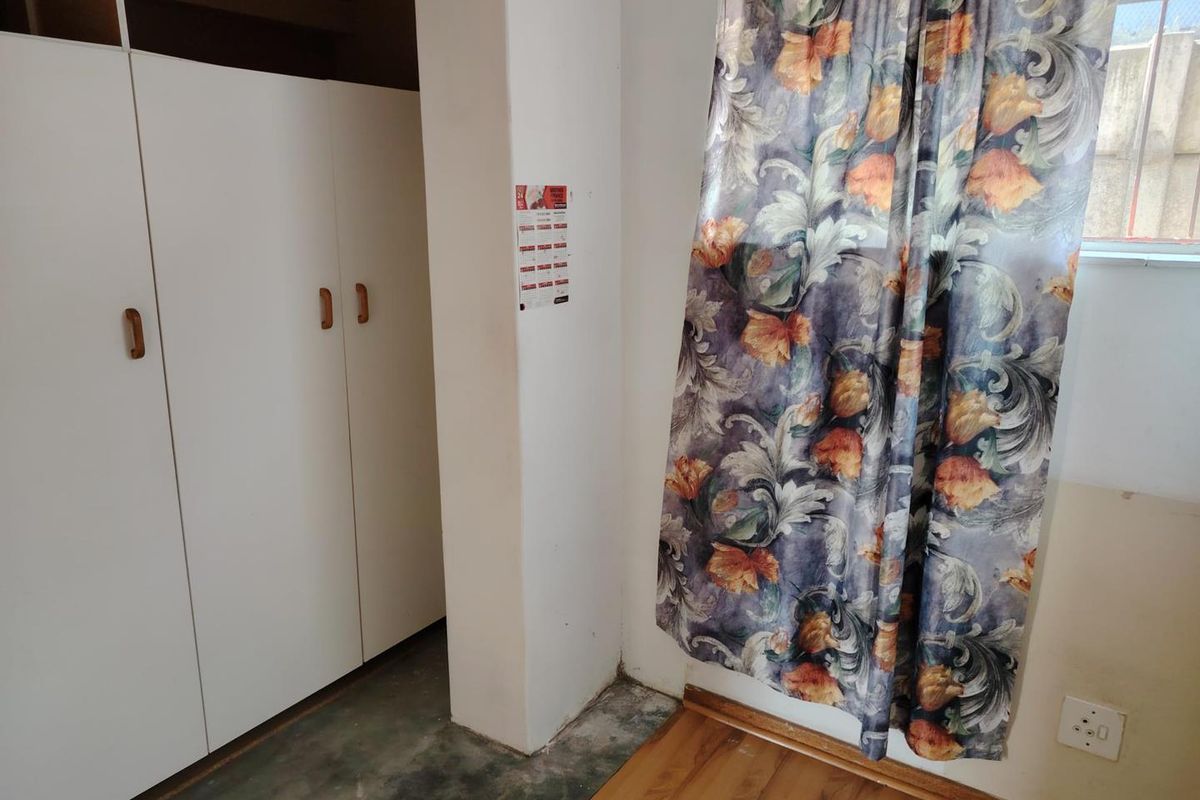 A bedroom featuring built-in cupboards and laminate flooring, requiring minor cosmetic updates to the floor transitions and finishes.