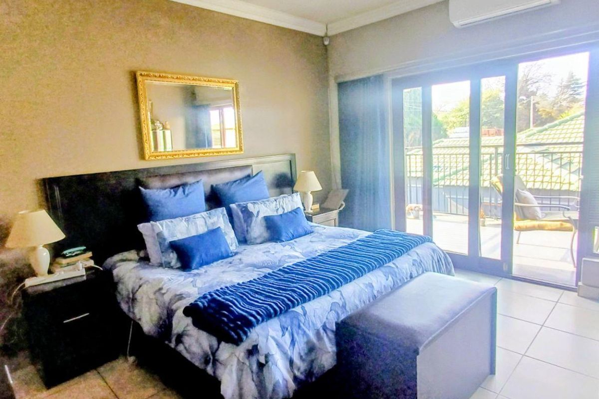 Spacious bedroom featuring tiled flooring, crown molding, an integrated air conditioning unit, and large sliding glass doors providing access to an outdoor balcony.