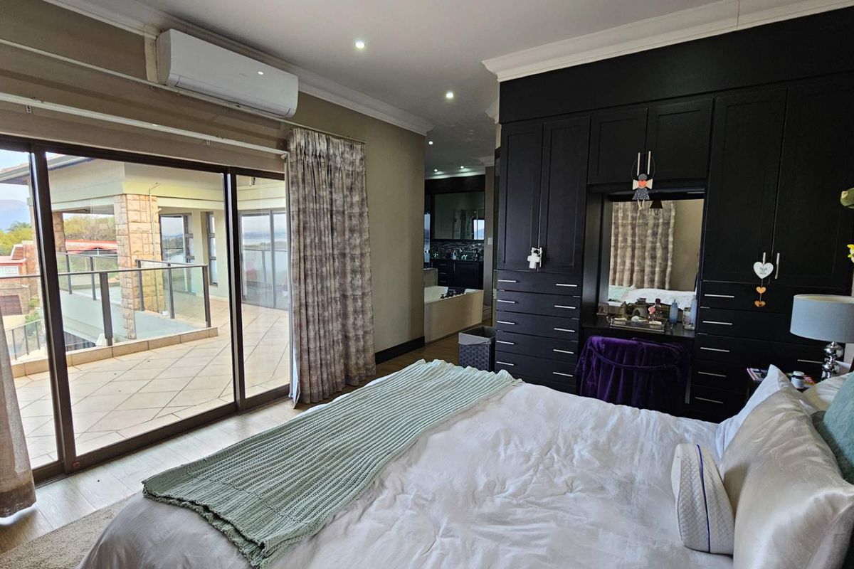 Spacious bedroom featuring extensive built-in cabinetry, air conditioning, and large sliding doors opening onto a private balcony with views.