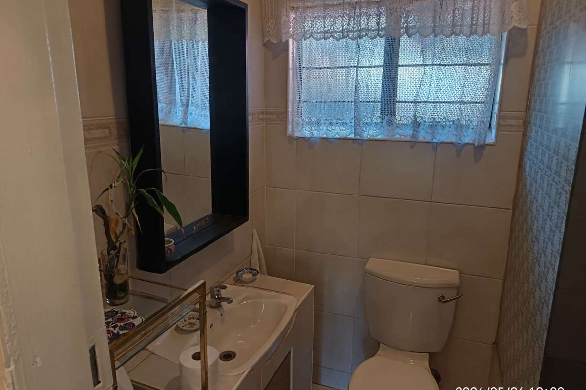 A functional bathroom featuring tiled walls, a built-in vanity with a basin, and a standard toilet.