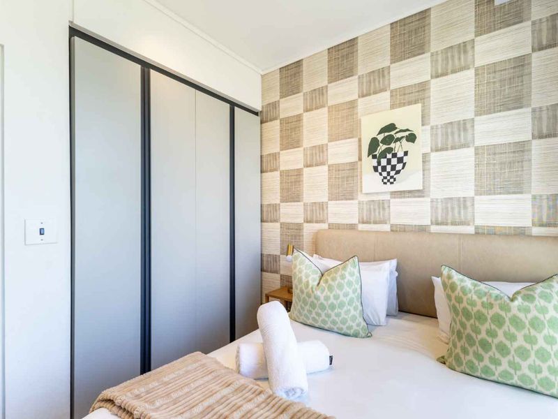 A well-maintained bedroom featuring a built-in wardrobe and a decorative textured feature wall.