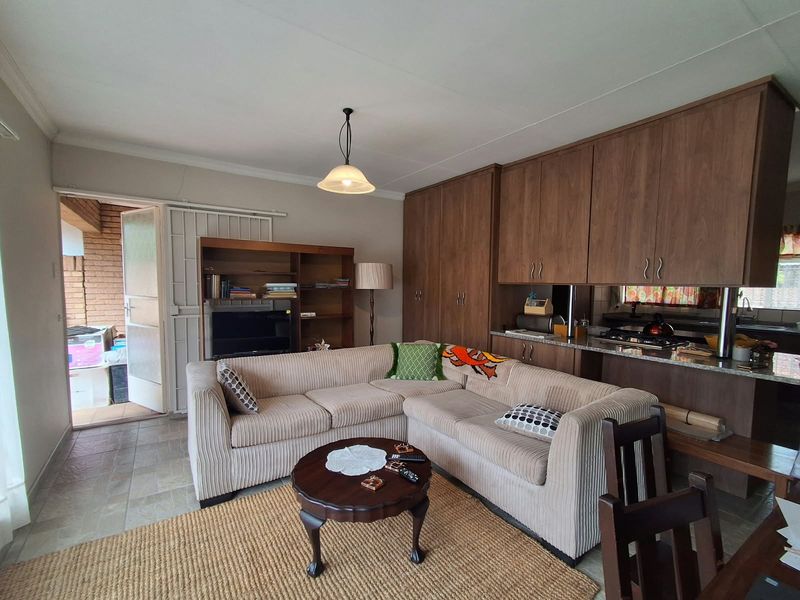 Open plan living area featuring built-in kitchen cabinetry with granite countertops and direct access to an outdoor patio area.