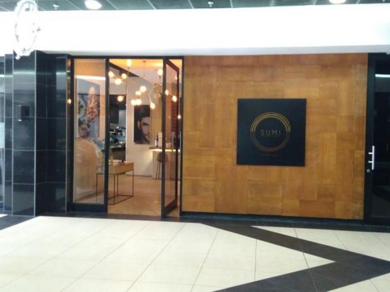 Modern commercial entrance featuring timber wall paneling, glass door access, and polished tiled flooring with recessed ceiling lighting.