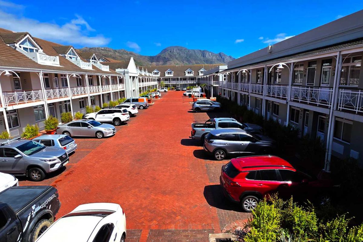 An elevated view of a well-maintained office complex courtyard featuring paved parking areas and multi-level building facades with balcony access.
