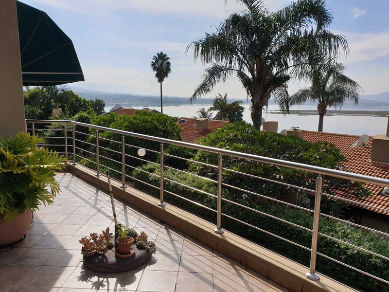 A spacious balcony featuring stainless steel railings and tiled flooring, offering scenic views of the surrounding landscape and water.