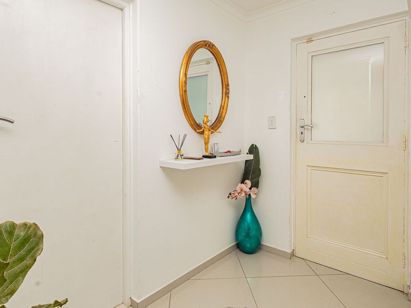 A functional entrance hall featuring tiled flooring and a glass-paneled external door, providing a clean and accessible entry point to the home.