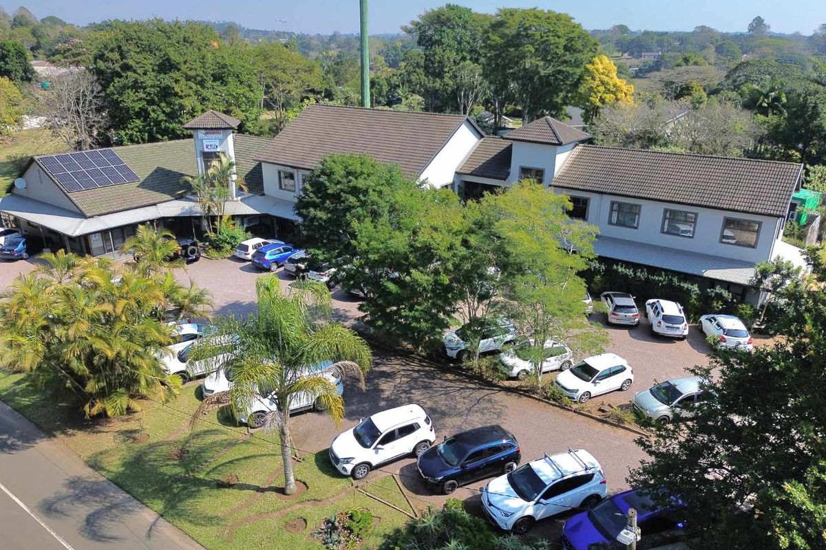 Aerial view of a commercial office park featuring multiple buildings, extensive paved parking, solar panel installations, and established landscaped grounds.