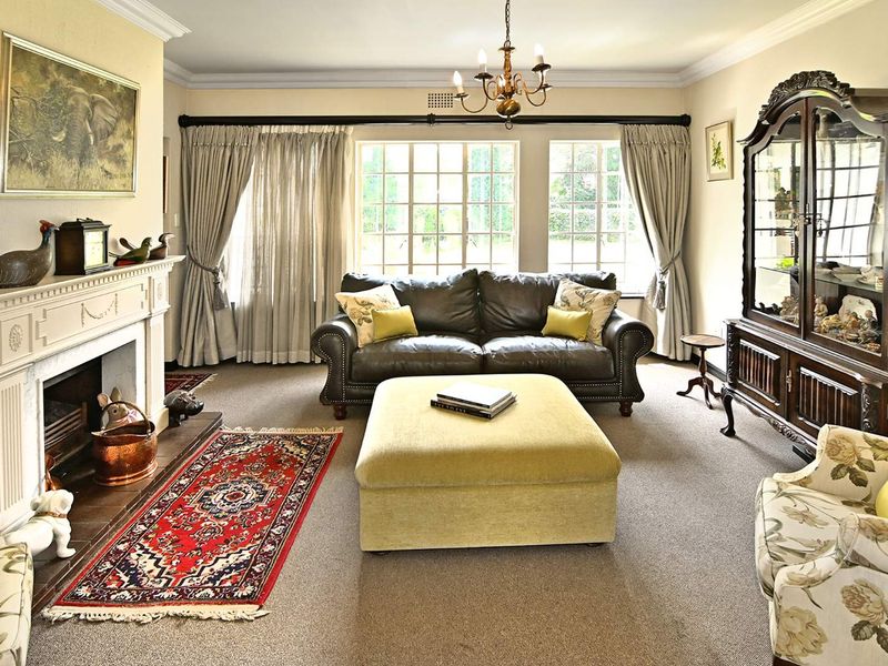 A traditional living room featuring a classic fireplace with a mantelpiece, crown molding, and large multi-pane windows providing natural light.