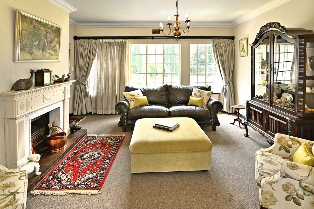 A traditional living room featuring a classic fireplace with a mantelpiece, crown molding, and large multi-pane windows providing natural light.
