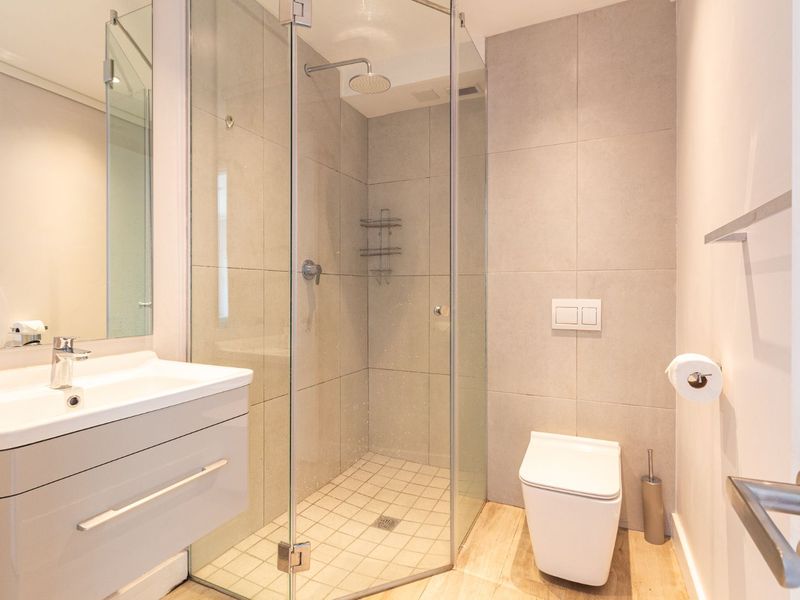 Modern bathroom featuring a wall-mounted vanity, glass-enclosed shower with rain head, and a wall-hung toilet with concealed cistern.