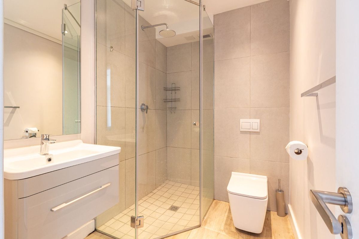 Modern bathroom featuring a wall-mounted vanity, glass-enclosed shower with rain head, and a wall-hung toilet with concealed cistern.