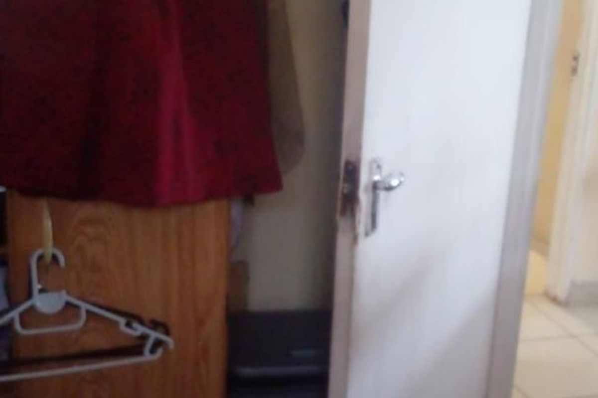 A view of a bedroom closet area with built-in shelving and a standard interior door leading to an adjacent tiled space.