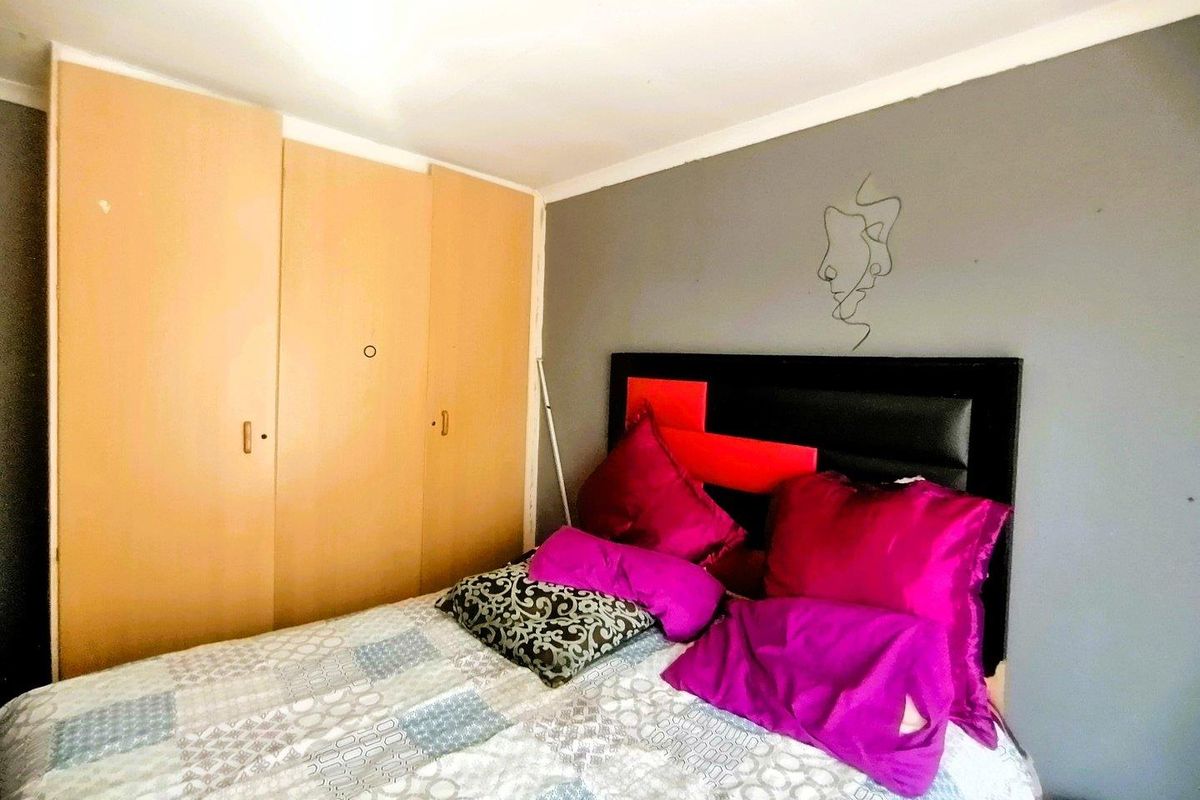 A bedroom featuring a built-in wardrobe with light wood-finish doors and a grey accent wall.