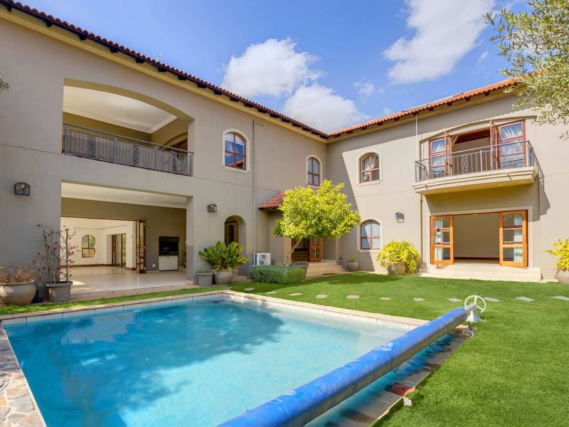 Spacious rear exterior featuring a swimming pool, manicured lawn, covered patio, and upper-level balconies, showcasing the property's well-maintained architectural design.