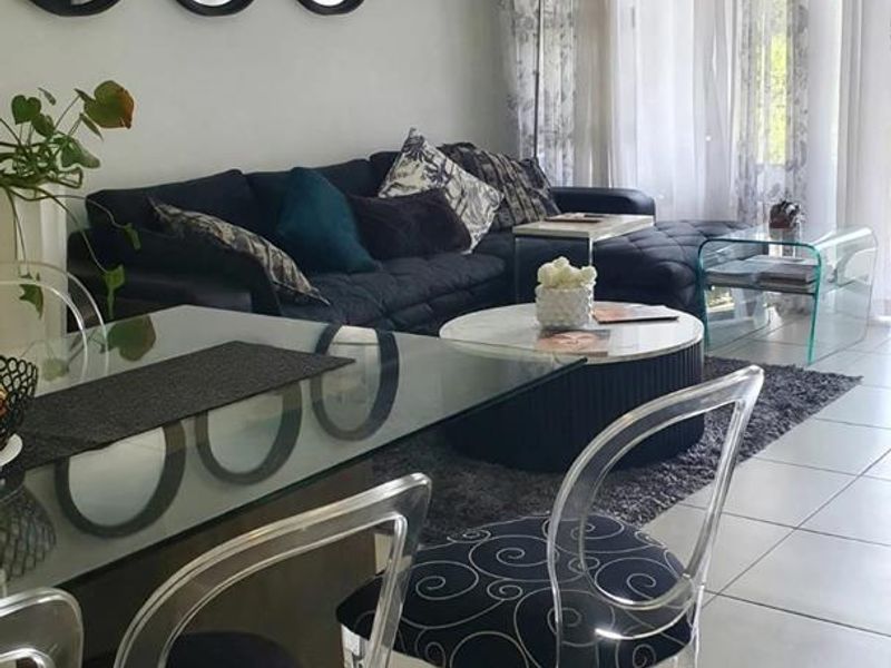 An open-plan living and dining area featuring neutral ceramic floor tiles and large sliding glass doors that provide ample natural light.
