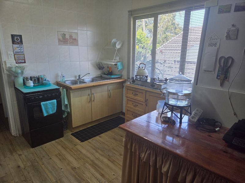 A functional kitchen featuring laminate countertops, a stainless steel sink, tiled splashback, and built-in cabinetry with a gas hob.
